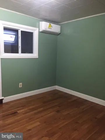 a view of a small space with wooden floor and mirror