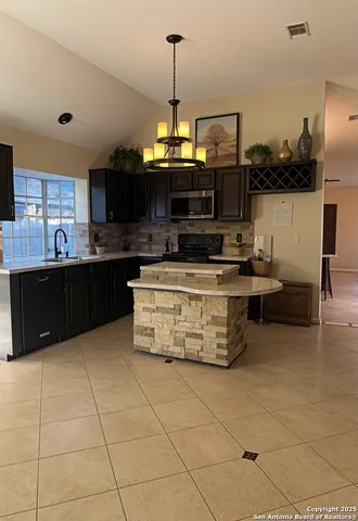 a kitchen with stainless steel appliances granite countertop a stove a sink and a microwave