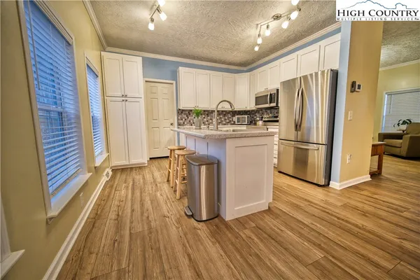 a kitchen with kitchen island wooden floors appliances and cabinets