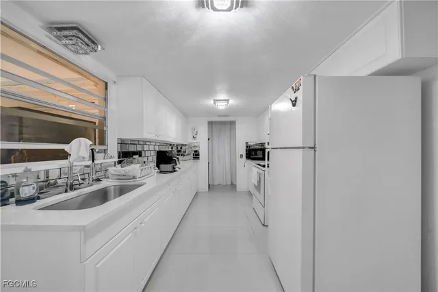 a kitchen with stainless steel appliances a refrigerator a sink a stove and white cabinets