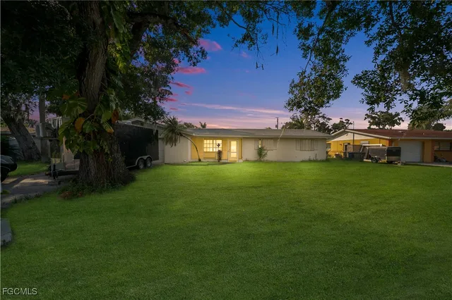 a front view of a house with garden and trees