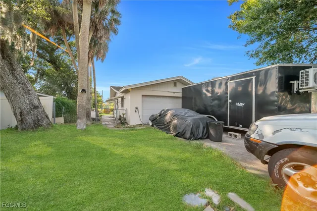 a view of a backyard with table and chairs potted plants and a large tree