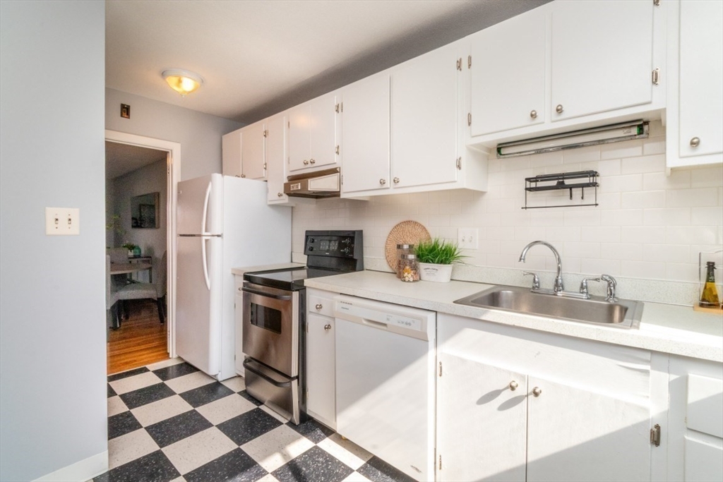57 St Paul Street, Unit 19 Brookline, MA 02446 - Photo 7 of 23 a kitchen with stainless steel appliances granite countertop a sink a stove a refrigerator and cabinets