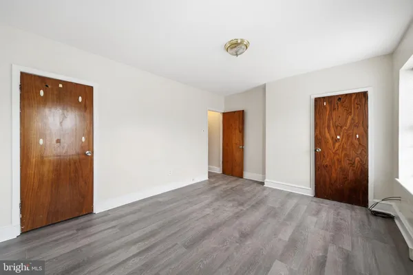 a view of an empty room with wooden floor and closet