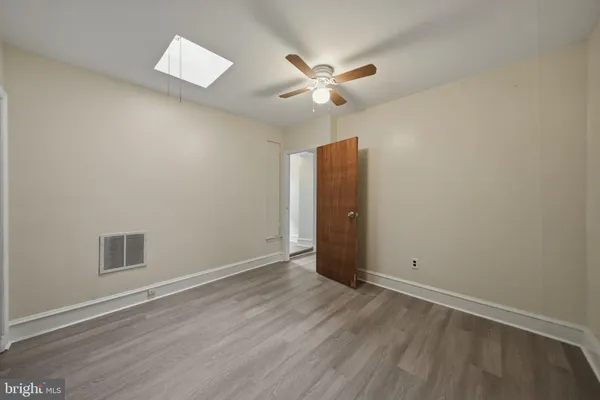 a view of an empty room with wooden floor and a ceiling fan