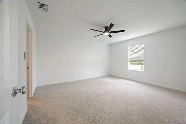 an empty room with a window and a ceiling fan