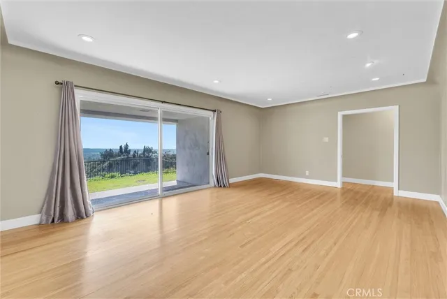 a view of an empty room with window and wooden floor