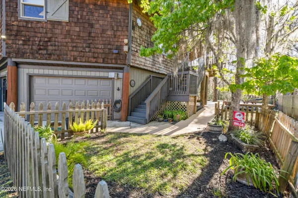 a view of a patio with table and chairs under an umbrella with a barbeque