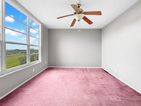 an empty room with a window and a fan