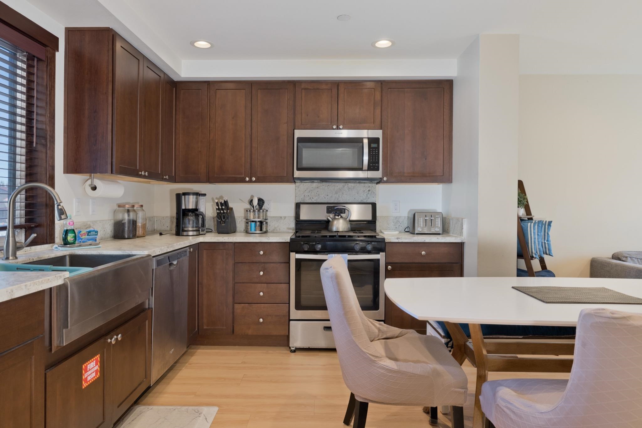 28 Oak Tree Way, Unit 8 Mammoth Lakes, CA 93546 - Photo 6 of 32 Kitchen featuring stainless steel appliances, dark wood finish cabinetry, light wood-style floors, recessed lighting, and light stone counters