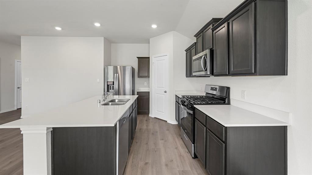 1913 Freeman Street Tyler, TX 75704 - Photo 2 of 21 Kitchen featuring stainless steel appliances, an island with sink, light wood-type flooring, recessed lighting, and light stone countertops