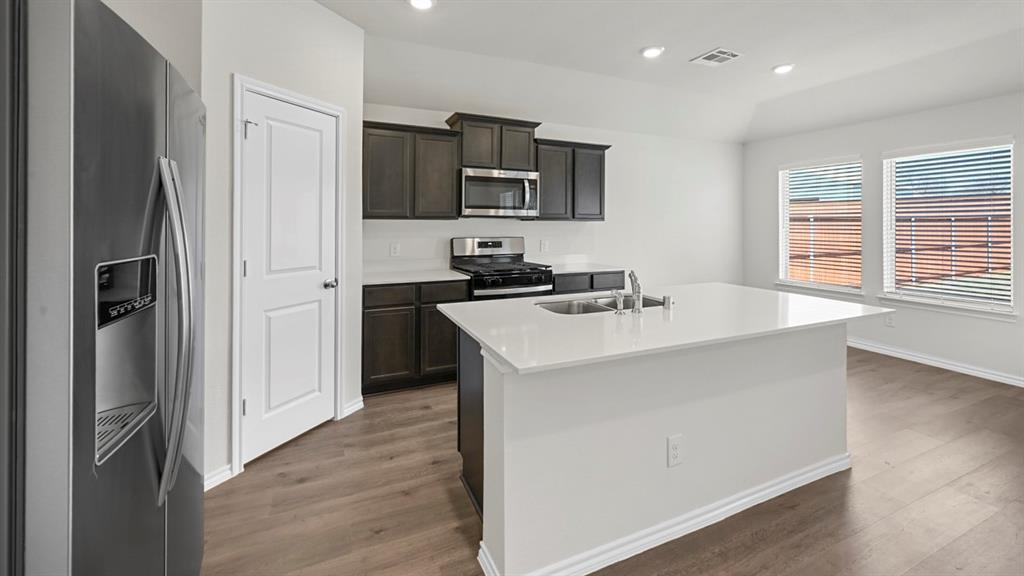 1913 Freeman Street Tyler, TX 75704 - Photo 4 of 21 Kitchen featuring stainless steel appliances, a kitchen island with sink, recessed lighting, dark wood-style floors, and light stone countertops