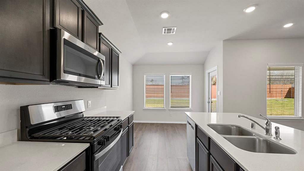 1913 Freeman Street Tyler, TX 75704 - Photo 7 of 21 Kitchen with stainless steel appliances, dark cabinetry, light wood-style floors, recessed lighting, and light stone counters