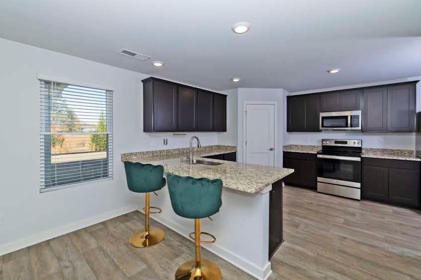 244 Overlook Road Covington, GA 30014 - Photo 7 of 24 a kitchen with stainless steel appliances granite countertop a stove top oven a sink dishwasher a dining table and chairs with wooden floor