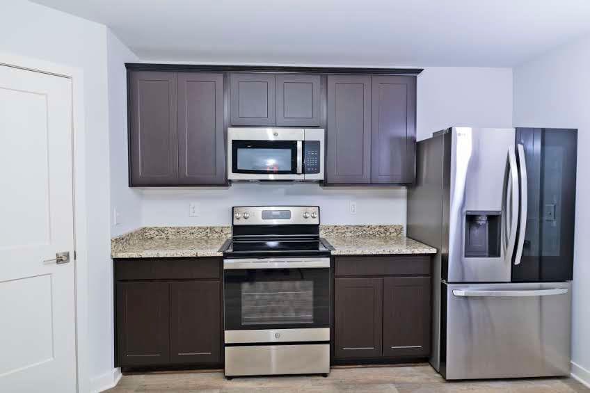 244 Overlook Road Covington, GA 30014 - Photo 9 of 24 a kitchen with granite countertop wooden cabinets a refrigerator and a stove