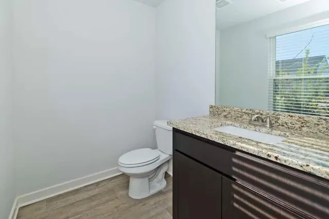 a bathroom with a granite countertop sink and a toilet