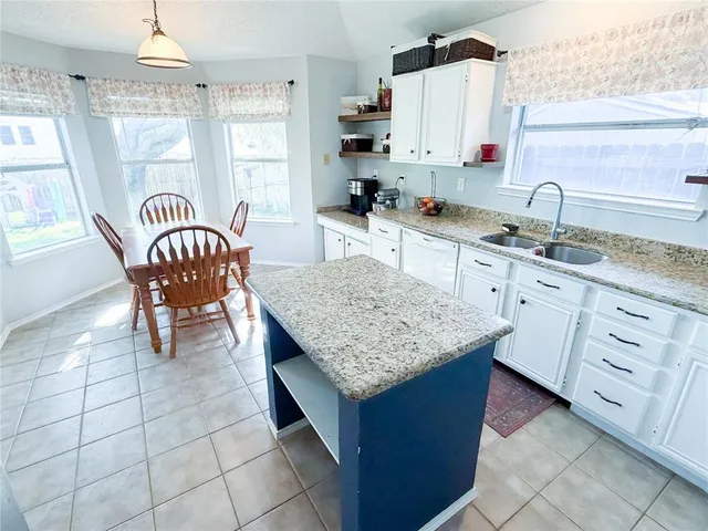 a kitchen with stainless steel appliances granite countertop a table chairs in it and a window