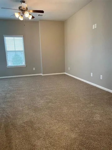an empty room with windows and chandelier fan