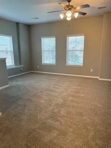 an empty room with windows and chandelier fan