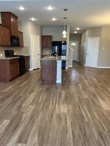 a kitchen with kitchen island a sink wooden floor and window