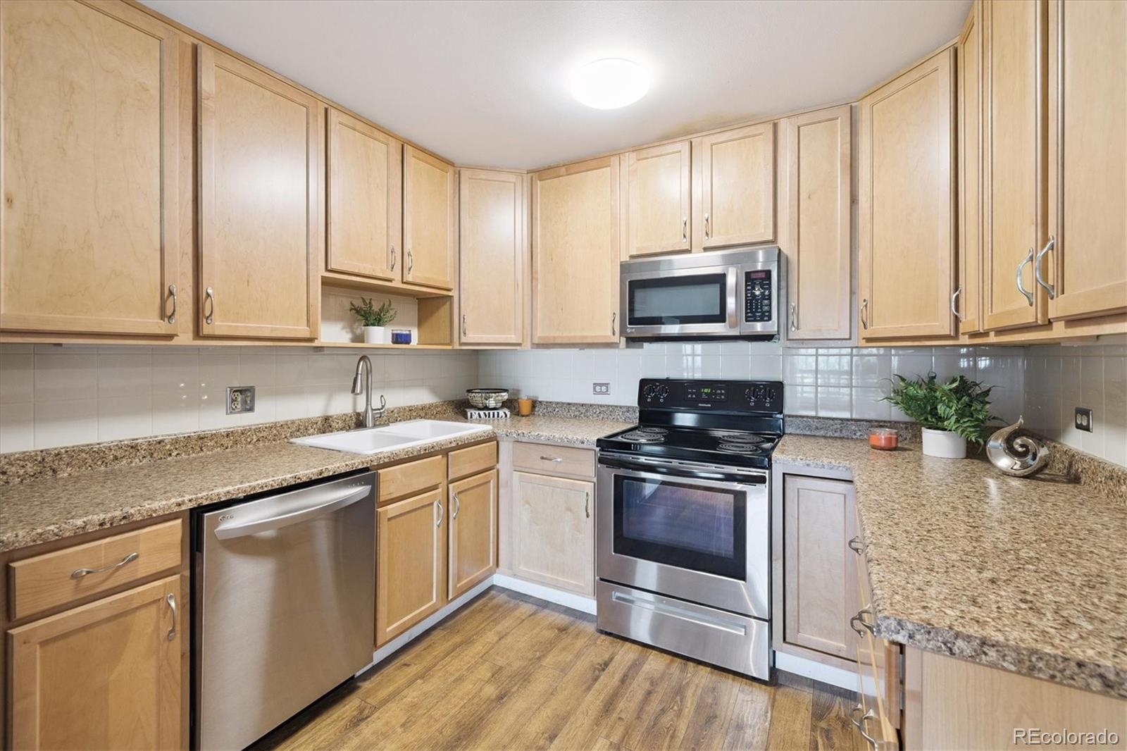 9155 Center Avenue, Unit 2D Denver, CO 80247 - Photo 4 of 50 a kitchen with stainless steel appliances granite countertop a stove a sink and a microwave