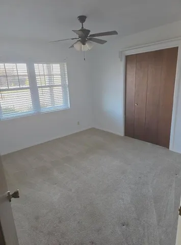 an empty room with windows and fan