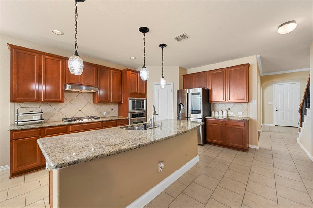 14815 Frisco Ranch Drive Little Elm, TX 75068 - Photo 8 of 40 a kitchen with stainless steel appliances granite countertop a sink a stove and a wooden cabinets