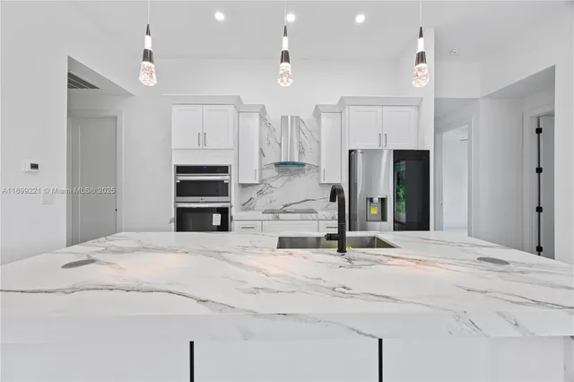 a kitchen with kitchen island granite countertop a sink cabinets and stainless steel appliances