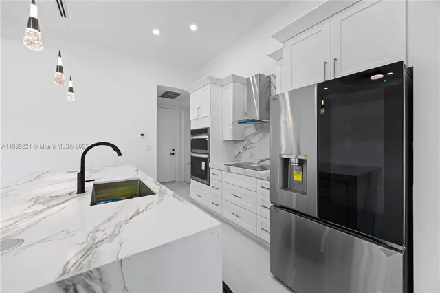 a kitchen with stainless steel appliances kitchen island a refrigerator sink and cabinets