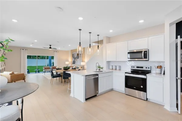 a kitchen with stainless steel appliances kitchen island granite countertop a refrigerator a stove a sink dishwasher and white cabinets with wooden floor
