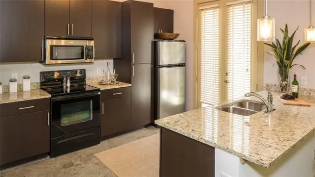 a kitchen with stainless steel appliances granite countertop a refrigerator a stove and a sink