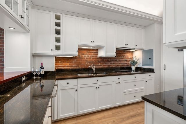 a kitchen with granite countertop a sink a stove and cabinets