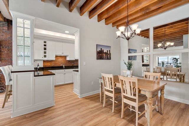 a dining room with stainless steel appliances kitchen island granite countertop furniture and wooden floor