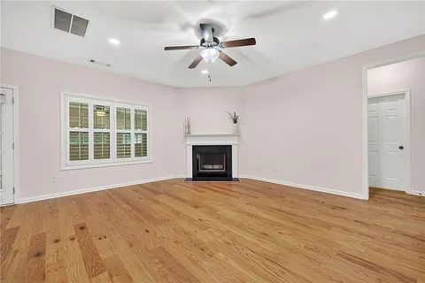 an empty room with wooden floor a ceiling fan and windows