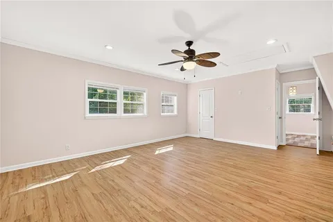 a view of empty room with wooden floor and fan