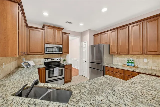 a kitchen with stainless steel appliances granite countertop a refrigerator sink and stove