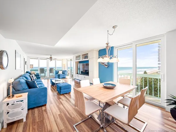a dining room with furniture wooden floor a rug a potted plant and a chandelier
