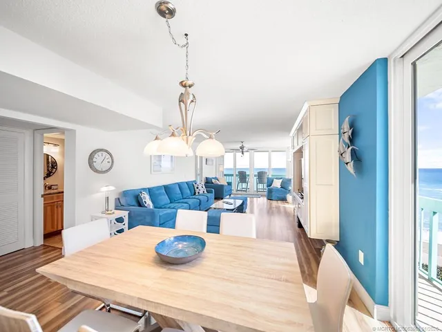 a view of a dining room and livingroom with furniture wooden floor a chandelier