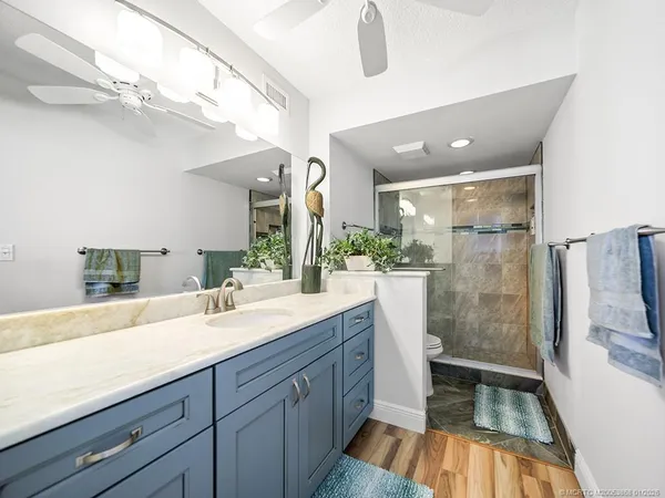 a spacious bathroom with a double vanity sink a large mirror and shower