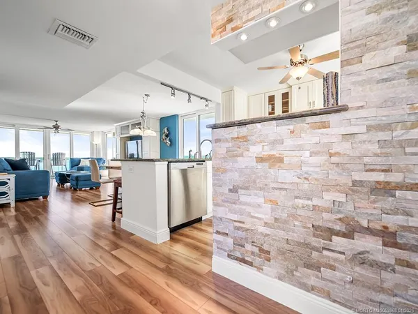 a living room with couches and kitchen view with wooden floor