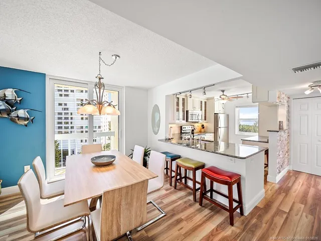 a room with stainless steel appliances kitchen island granite countertop furniture and a dining table