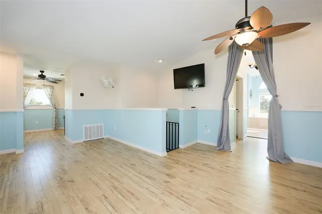 a view of a livingroom with wooden floor and a ceiling fan