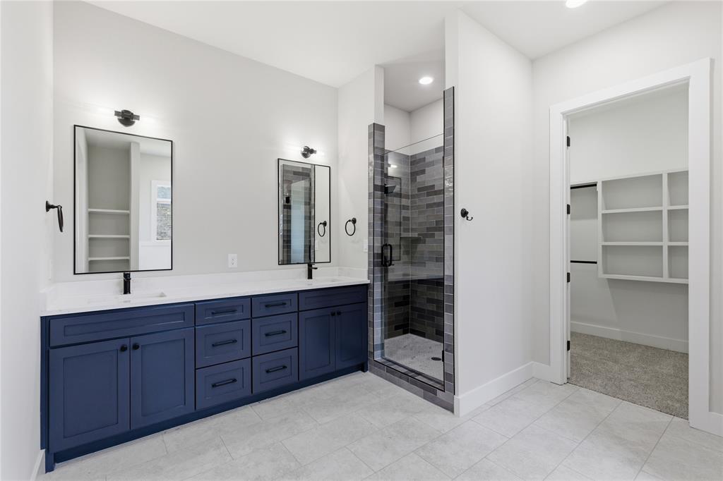 713 Anne Road Van Alstyne, TX 75495 - Photo 11 of 29 Bathroom featuring a dual vanity with navy cabinetry, matte black hardware, and rectangular mirrors
