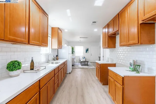 a kitchen with stainless steel appliances kitchen island granite countertop a sink a stove top oven a counter space and cabinets