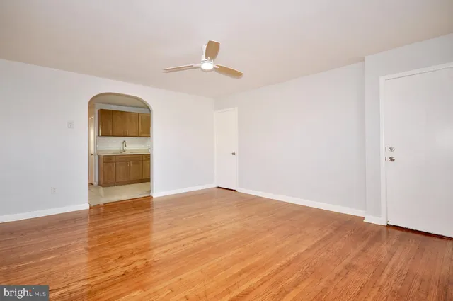 an empty room with wooden floor cabinet and a ceiling fan