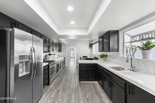 a kitchen with stainless steel appliances a sink a stove a refrigerator and cabinets