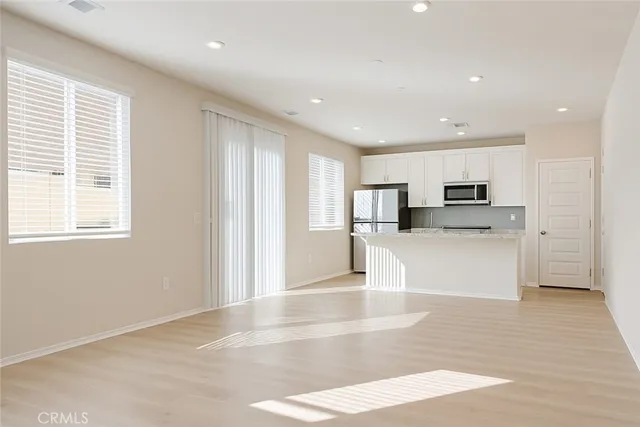 a view of kitchen with stainless steel appliances kitchen island granite countertop a stove a sink and white cabinets