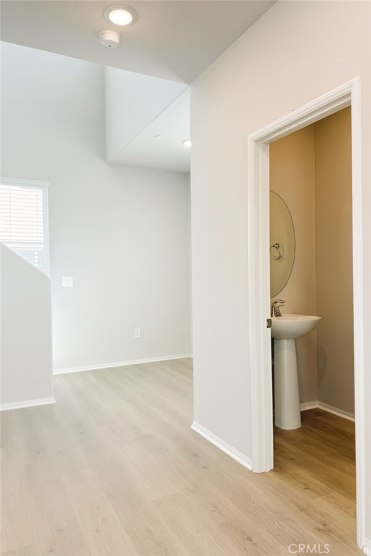 1120 Tropic Court, Unit 306 Redlands, CA 92374 - Photo 5 of 18 an empty room with mirror and a wooden floor