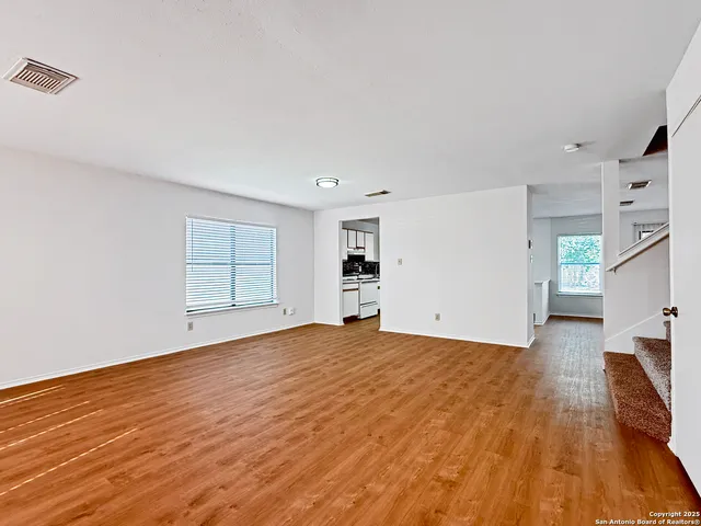 a view of empty room with wooden floor and window