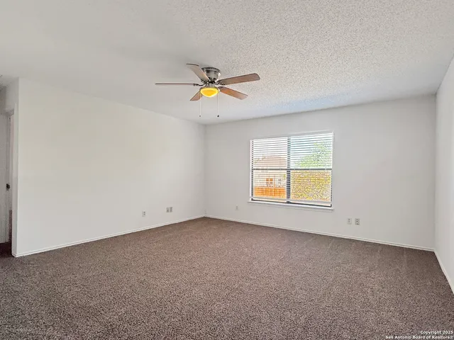 an empty room with windows and fan